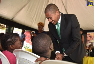 Minister of State in the Ministry of Education, Youth and Information, Hon. Floyd Green, interacts with children from the Walker’s Place of Safety during a ceremony to hand over a cheque for the rebuilding of the facility, held in January at Hope Zoo, St. Andrew.