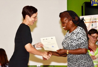 Foreign Affairs and Foreign Trade Minister, Senator the Hon. Kamina Johnson Smith (left), presents participant, Martha Corbett-Baugh, with a certificate of participation for successfully completing an intensive training programme for Spanish language practitioners, at the Shortwood Teachers’ College in St. Andrew, on August 21. 