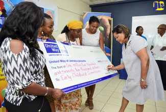 Board Chairman of United Way of Jamaica, Dr. Marcia Forbes (right), affixes her signature to the symbolic cheque for $1.472 million, which will be used to assist six basic schools with their preparations to become certified with the Early Childhood Commission (ECC), during a ceremony held at the offices of the National Volunteer Centre, Camp Road, in Kingston, on August 16. Observing (from left) are:  Principal, Sanguinetti Early Childhood Institution, Diana Douse; Principal, Nutshell Basic School, Eunice Johnson; Chairman, Nutshell Basic School, Yulanda Goehagon; and Chairperson of the ECC, Mrs. Trisha Williams-Singh.