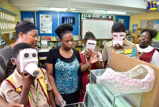 Young Innovators/Inventors Science Club Coordinator, Seaview Gardens Primary School, Racquel Rose Taylor (third left), outlines features of the ‘Emergency Respirator (ER)’ project, which won the school first place in the primary school category of the Scientific Research Council’s (SRC) National Science and Technology Fair and Competition in 2016/17. Club members Jadon Willis (left), Rihanna Hinds (third right), and Akail Black (second right), demonstrate how the respirator works. Looking on are School Principal, Sangieanna Reid Prince (second left); and club member, Sue Ann Jones (right).    