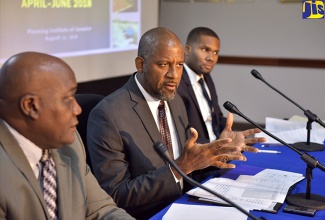 Planning Institute of Jamaica (PIOJ) Director General, Dr. Wayne Henry (centre), addresses journalists during the PIOJ’s recent quarterly media briefing at the agency’s head office in New Kingston. Listening (from left) are: Senior Director for the PIOJ’s Economic Planning, Research and Policy Division, James Stewart; and Economic Development Specialist in the PIOJ’s Vision 2030 Jamaica Secretariat, Travis Reid.