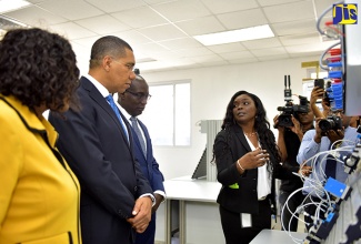 Prime Minister, the Most Hon. Andrew Holness (second left), and Education, Youth and Information Minister, Senator the Hon. Ruel Reid (second right), are briefed on operations in the pneumatics laboratory of the Festo Authorised and Certified Training (FACT) Centre at the Caribbean Maritime University (CMU) in Kingston, by FACT-certified trainer, Kadian Valentine (right). The occasion was a tour of the facility following its official opening by Prime Minister Holness on Wednesday (September 19). Looking on is Permanent Secretary in the Office of the Prime Minister, Audrey Sewell.