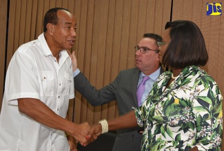 Minister without Portfolio in the Ministry of Economic Growth and Job Creation, Hon. Daryl Vaz (second right),  and Member of Parliament for East Rural St. Andrew, the Most Hon. Juliet Holness (right), speak with philanthropist and businessman, Michael Lee-Chin, who has donated $60 million to the industry that will be made available to needy coffee farmers.  Occasion was a media briefing regarding the coffee industry at the New Kingston offices of the Ministry of Industry, Commerce, Agriculture and Fisheries, on Monday (September 10). 