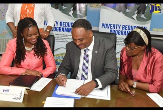 Jamaica Social Investment Fund (JSIF) Managing Director, Omar Sweeney (centre), signs a contract for implementation of the $18-million Behaviour Modification Initiative/Community-based Behaviour Change Programme, at the agency’s head office in New Kingston on Tuesday (September 18). The initiative, which forms part of phase four of the European Union (EU)-funded Poverty Reduction Programme (PRP IV), aims to reduce deviant behaviour among at-risk youth, aged eight to 25, in volatile and vulnerable communities in five parishes, through a range of social services and interventions. Observing  are representatives of two of the stakeholder partners (from left): Head, University of the West Indies Social Welfare Centre, Cerita Buchanan; and Executive Director, Family and Parenting Centre, Dr. Beverley Scott.