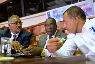 Minister of Education, Youth and Information, Senator the Hon. Ruel Reid (centre), listens to Minister of Health, Dr. the Hon. Christopher Tufton (left), at the  Choose Life International (CLI) World Suicide Prevention Day (WSPD) Seminar, held on Friday (September 14), at the Jamaica Conference Centre in Kingston.  At left is  President and Founder of CLI, Dr. Donovan Thomas.  