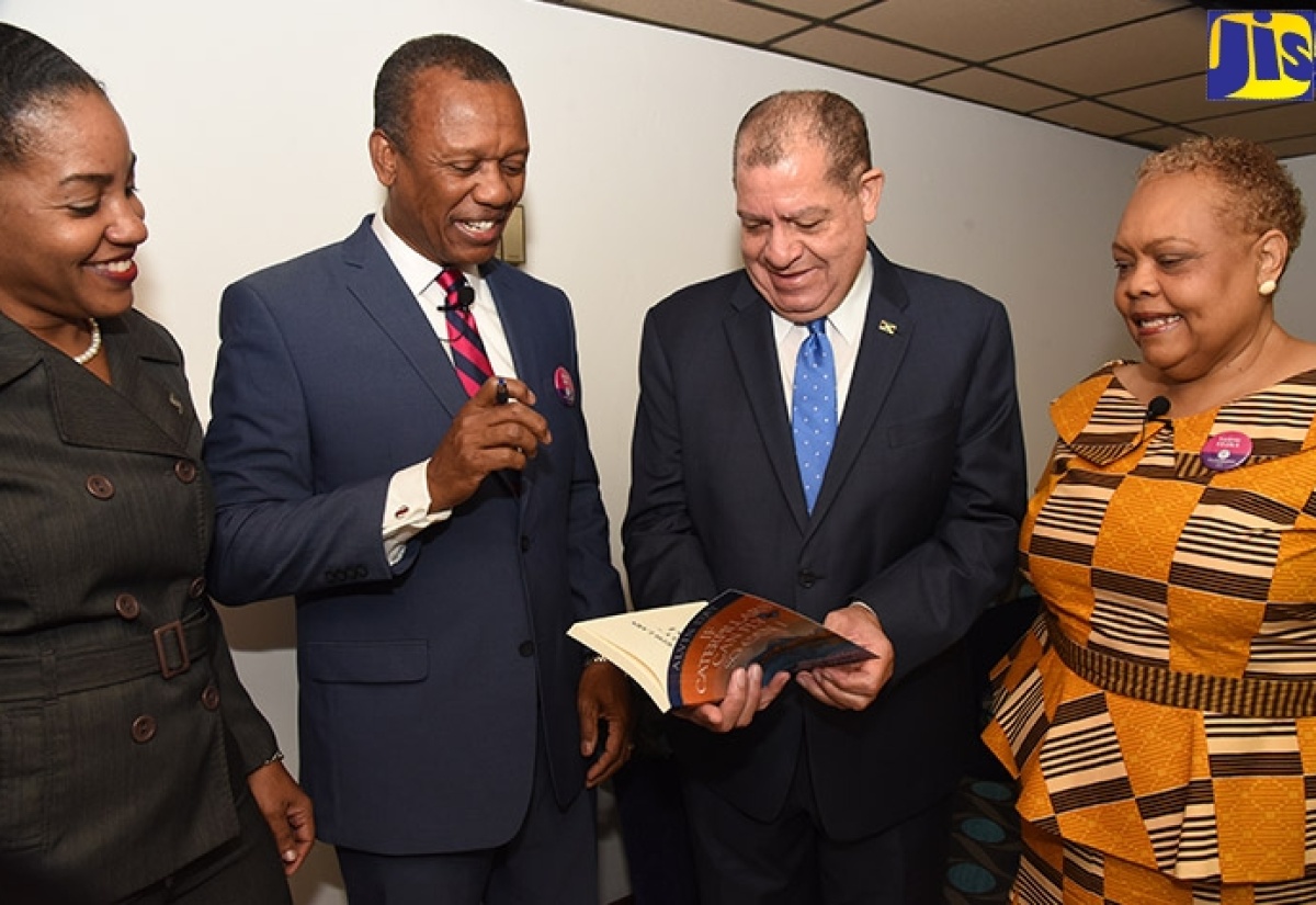 Minister of Industry, Commerce, Agriculture and Fisheries, Hon. Audley Shaw (second right), reading his signed copy of the book, ‘If Caterpillars Can Fly, So Can I’, from Author and Motivational Speaker, Alvin Day (second left), at the Jamaica Business Development Corporation (JBDC) Employee Engagement Conference 2018, which was held at Jamaica Conference Centre in downtown Kingston on Monday (October 22). Sharing in the moment are Small Business Director, Scotiabank Jamaica, Avril Leonce (left) and Chief Executive Officer, JBDC, Valerie Veira. 