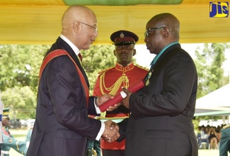 Governor-General, His Excellency the Most Hon. Sir Patrick Allen (left), presents the Badge of Honour for Long and Faithful Service to Councillor for the Gordon Town Division (East Rural St Andrew), Neville Whittaker Snr. (right), at the National Honours and Awards Ceremony, held on the lawns of King’s House on October 15. 