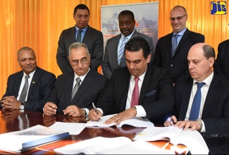 Prime Minister, the Most Hon. Andrew Holness (left, standing); and Transport and Mining Minister, Hon. Robert Montague (2nd left, standing), observe as  Chief Executive Officer of Mexican entity, Grupo Aeroportuario del Pacifico S.A.B. De C.V. (GAP), Raul Revuelta Musalem (2nd right, seated), signs the 25-year Norman Manley International Airport concession agreement on Wednesday (October 10). The signing took place at the Office of the Prime Minister. Also observing (from left, seated) are: President and Chief Executive Officer, Airports Authority of Jamaica (AAJ), Audley Deidrick; AAJ Chairman, Hon. William Shagoury; and Head of GAP  subsidiary, PAC Kingston Airport Limited, Saul Villarreal Garcia. At right (standing) is NMIA Enterprise Team Chairman, Paul B. Scott.