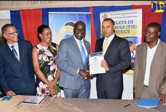 Minister of Education, Youth and Information, Senator the Hon. Ruel Reid (centre), shakes hands with Chief Executive Officer (CEO) Innovative Corporate Solutions, Neil Abrahams (second right), following the signing of a contract for a new phase of the Tablets in Schools Project at the Terra Nova All-Suite Hotel in St. Andrew on October 30. Sharing the occasion  (from left) are Acting CEO, e-Learning Jamaica Company Limited, Izett McCalla; CEO, GeoTechVision, Valerie Grant; and Principal Financial Officer, Ministry of Science and Technology, Richard Fonseca. Contracts totalling US$30 million were signed with GeoTechVision and Innovative Corporate Solutions.