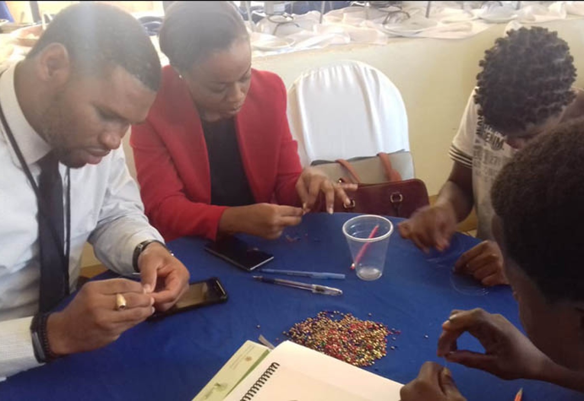 Probation Aftercare Officers, André Foster (left) and Prisca Parkinson (econd left), working with probationers in making beaded jewellery at the final in the series of anti-gang sensitisation sessions held at Hotel Grandiosa in Montego Bay, St. James, on Wednesday (November 7).