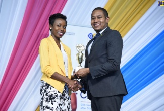 Minister of State in the Ministry of Education, Youth and Information, Hon. Floyd Green (right), presents teacher at the St. Thomas-based Morant Bay High School, Moesha Brown, with the trophy for being the Most Outstanding Career Advancement Programme (CAP) School. Occasion was a graduation ceremony for over 3,000 CAP students, held on December 3 at the National Indoor Sports Complex in St. Andrew.

