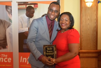 Permanent Secretary in the Ministry of Education, Youth and Information, Dean-Roy  Bernard (left) accepts an award from Chief Executive Officer of the National Parenting Support Commission (NPSC) , Kaysia Kerr (right),  for his participation and support of the Commission’s programmes and activities during Parent Month in November. The occasion was the NPSC’s National Parent Awards Ceremony, held at Hotel RIU Montego Bay in St. James on Friday (November 30).