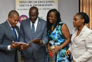 Minister of Education, Youth and Information, Senator the Hon. Ruel Reid (second left) and State Minister in the Ministry, Floyd Green, peruse the new Cheetah Primary Exit Profile (PEP) text book at the Ministry's Quarterly Press Briefing, which was held at their offices in downtown Kingston on Thursday (December 6). Sharing the moment are Authors of Cheetah PEP practice books, Dr. Paulette Trowers (second right) and Dr. Stephanie Mullings.