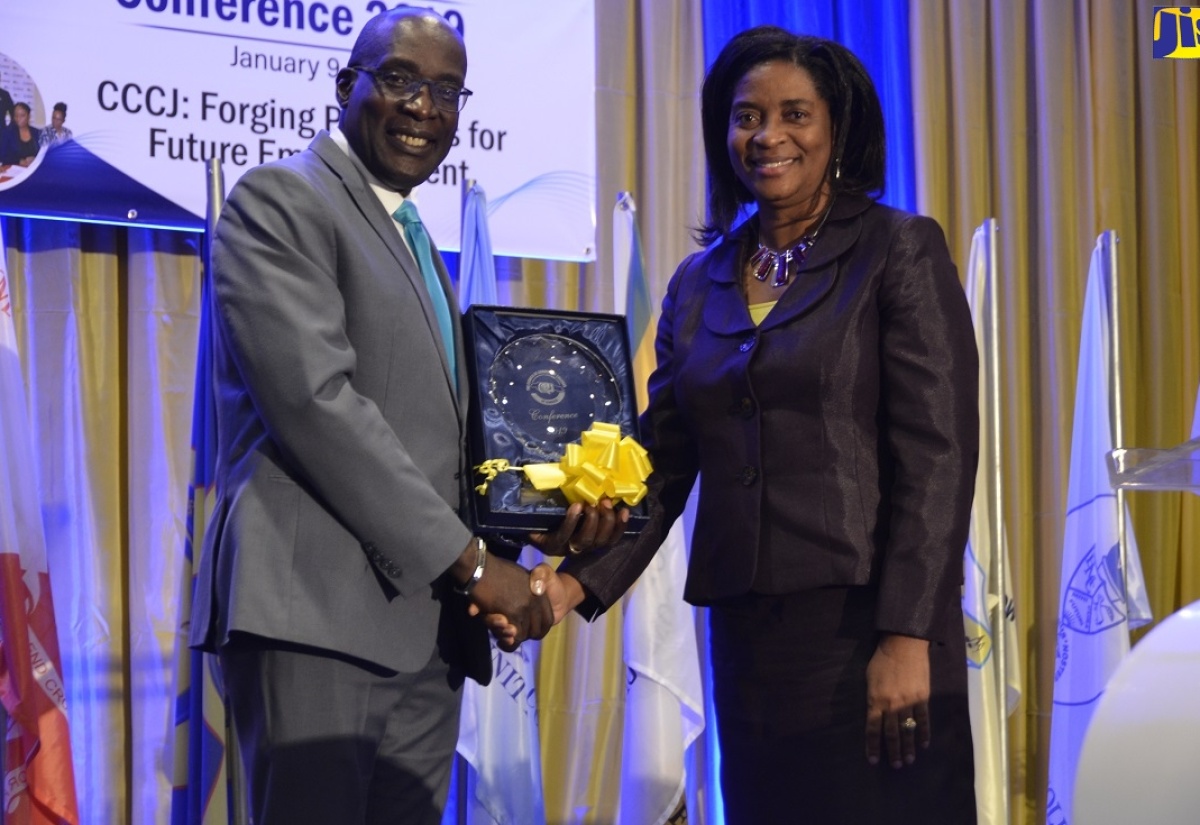 Minister of Education, Youth and Information, Senator the Hon. Ruel Reid (left), accepts a gift from Principal of the Trench Town Polytechnic College, Dr. Dosseth Edwards-Watson, following his keynote address at the annual conference of the Council of Community Colleges of Jamaica (CCCJ) held at the Hilton Rose Hall Resort and Spa in St James on January 9.