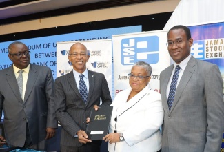 Managing Director of the Development Bank of Jamaica, Milverton Reynolds (second left); and Managing Director of the Jamaica Stock Exchange (JSE), Marlene Street Forrest (second right), display a signed MOU at the JSE’s 14th regional Investments and Capital Markets Conference at The Jamaica Pegasus hotel in New Kingston, on January 23. Sharing the moment (from left) are Principal of the JSE eCampus, Samuel Parkes, and Finance and the Public Service Minister, Dr. the Hon. Nigel Clarke. 