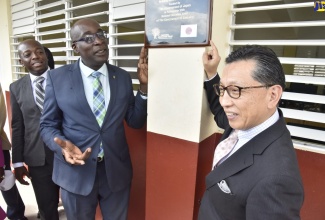 Minister of Education, Youth and Information, Senator the Hon. Ruel Reid (centre), and Japan's Ambassador to Jamaica, His Excellency Hiromasa Yamazaki (right), point to the plaque dedicating the learning centre at the Rock River Primary School in Clarendon, at the official opening of the facility on January 29. Looking on at left is Minister of State for Foreign Affairs and Foreign Trade, Senator the Hon. Pearnel Charles Jr. 
 
