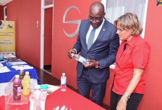 Minister of Education, Youth and Information, Senator Hon. Ruel Reid (left), and Executive Director of the Heart Foundation of Jamaica, Deborah Chen, peruse details on the label of a beverage bottle, during a forum on ‘Sugars, Other Carbohydrates and Fats - Their Contribution to Obesity… and Effective Solutions’,  at the Spanish Court Hotel in New Kingston on Jan. 11.

