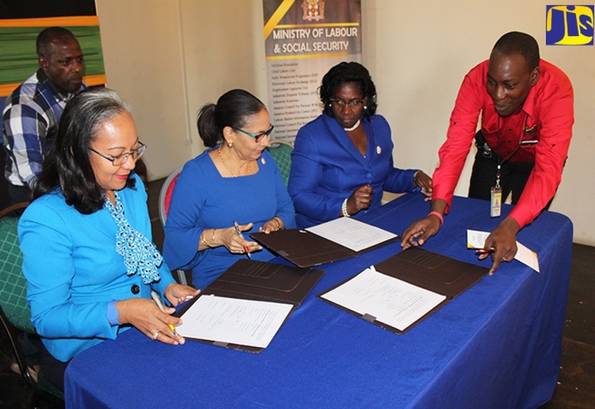 Labour Component Coordinator at the Ministry of Labour and Social Security, Lyndon Ford (right), coordinates the signing of a Memorandum of Understand between the Ministry  and Montego Bay Community College (MBCC), recently. Signing on behalf of  the Ministry are  Minister Shahine Robinson (second left);  Permanent Secretary, Collete Roberts Risden (left) and Principal of MBCC, Dr. Maureen Nelson.