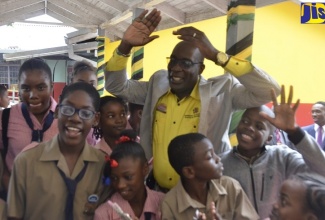 Minister of Education, Youth and Information, Senator the Hon Ruel Reid, celebrates with students of Hoolebury Primary School, Scarlett Hall, Runaway Bay, St. Ann, following their completion of the first sitting of the Primary Exit Profile (PEP) Examination, during a visit to the institution on February 26.