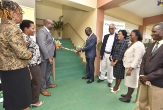 Education, Youth and Information Minister, Senator the Hon. Ruel Reid (fifth right), cuts the ribbon to officially open the Educational Assessment and Resource Centre at the Church Teachers' College in Mandeville, Manchester, on  February 19. Assisting the Minister is 
Jamaica Teachers' Association (JTA) President and Principal of the college, Dr. Garth Anderson (third left), while officials from the Ministry and the college look on. 
