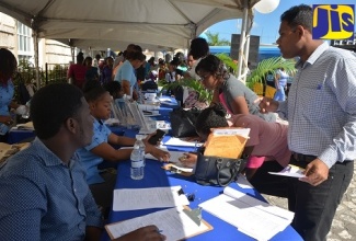 HEART Trust/NTA representatives (seated at left), provide members of the public with information on training programmes, at a Career Youth and Information Forum and Exposition held at Sam Sharpe Square in Montego Bay on Tuesday (February 12). 
 
