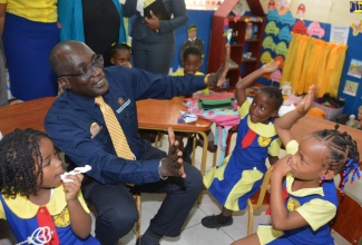 Minister of Education, Youth and Information, Senator the Hon. Ruel Reid, interacts with students of the Liberty Hill Infant School in Discovery Bay, St. Ann, at the institution’s reopening on Wednesday (February 20).