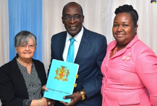 Minister of Education, Youth and Information, Senator the Hon. Ruel Reid (centre), hands over a signed Memorandum of Understanding (MOU) to Representative, Christel House International, Sally Porteous (left), for the establishment of a Christel House School in Jamaica. The signing took place on Monday (March 18) at the Ministry's offices in Kingtson. Sharing the moment is Permanent Secretary in the Ministry, Dr. Grace McLean. 