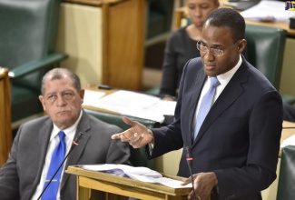 Minister of Finance and the Public Service, Dr. the Hon. Nigel Clarke, announces the Revenue Measures for the financial year 2019/20, as he opens the 2019/20 Budget debate in the House of Representatives on March 7. Seated from left are: Industry, Commerce, Agriculture and Fisheries Minister, Hon. Audley Shaw and Minister of Science, Energy and Technology, Hon. Fayval Williams.