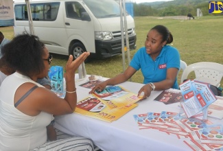 Manager for the Trafficking in Persons Unit in the Ministry of Justice, Chenee Russell (right), listens attentively to a concerned resident of Steer Town in St. Ann, during a Justice Fair hosted in the community by the Legal Aid Council March 22

