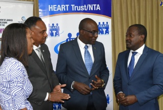 Education, Youth and Information Minister, Senator the Hon. Ruel Reid (second right), speaks to HEART Trust/NTA Chairman, Edward Gabbidon (right), at a contract signing ceremony between the Jamaica Social Investment Fund (JSIF) and the HEART Trust/NTA to train ancillary workers in schools, at JSIF’s headquarters, in Kingston, on March 7.  Also sharing in the dialogue are (from left): General Manager of Technical Services at JSIF, Loy Malcolm, and JSIF Managing Director, Omar Sweeney.