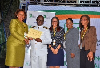 Chairman of the University Council of Jamaica (UCJ), Dr. Carolyn Hayle (left), presents Deputy President of the Caribbean Maritime University (CMU), who is also Vice President of Academic and Student Affairs at the institution, Professor Ibrahim Ajagunna (second left), with a certificate of candidacy for institutional accreditation at an awards ceremony held during the UCJ’s Symposium on Quality Assurance in Higher Education on March 12, at the Iberostar Hotel in Montego Bay, St. James. Sharing in the moment (from third left) are Executive/Research Assistant to Professor Ibrahim Ajagunna, Lanna-Gaye Franklyn Green; Administrative Assistant to the Dean of General Studies at the CMU, Carlene McKinson; and CMU Consultant, Sonia Warmington.  