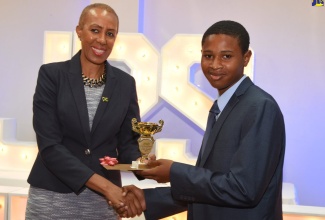 Science, Energy and Technology Minister, Hon. Fayval Williams (left), presents a trophy and $20,000 bursary to Ardenne High School student, Alexio Fraser, who was awarded for outstanding performance in the 2018 Caribbean Secondary Education Certificate (CSEC) Industrial Technology examination. The presentation was made during an awards ceremony hosted by the Jamaica Public Service (JPS) Foundation for top students in the 2018 examination, at Hotel Four Seasons in Kingston on April 16. 