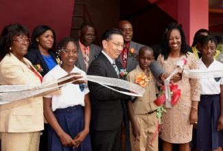 Japan's Ambassador to Jamaica, His Excellency Hiromasa Yamazaki (third left), and Member of Parliament for South Manchester, Michael Stewart (third right), cut the ribbon to open the newly rebuilt Campbell’s Castle Primary School in South Manchester on Monday (April 8). Sharing the moment (from left) are Chairman of the School Board, Maureen Tomlinson; students, Khadijah Napier and Jordon Anderson; Principal, Petagaye Campbell; and student, Dejaneca Pryce. 