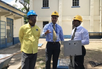 Minister without Portfolio in the Ministry of Economic Growth and Job Creation, Hon. Pearnel Charles Jr (right), and Plant Manager, National Water Commission (NWC) Constant Spring Water Treatment Plant,  Patrick Gordon (left) listen to a point from NWC President, Mark Burnett, during a tour of the Constant Spring plant in St. Andrew on Wednesday (May 15). 