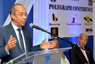 Minister of National Security, Hon. Dr. Horace Chang, addressing the Canadian Association of Police Polygraphists Region 7 Conference at The Jamaica Pegasus hotel in New Kingston on May 27. Listening are Region Director, Marchan Gittens; and Director General of  the Major Organised Crime and Anti-Corruption Agency, Col. Desmond Edwards. 