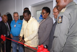 Minister of Transport and Mining, Hon. Robert Montague (third left), cuts the ribbon to symbolise the official opening of a pilot lounge at the Tinson Pen Aerodrome in St. Andrew on Thursday (May 16). Others pictured (from left) are Deputy Mayor of Kingston, Winston Ennis; Custos of Clarendon, William Shagoury; Member of Parliament for South West St. Andrew, Dr. Angela Brown-Burke;  President  and Chief Executive Officer of the Airports Authority of Jamaica (AAJ),  Audley Deidrick; and  Captain Denver Ennis of the Jamaica Defence Force (JDF). Mr. Montague has mandated that all Jamaican aerodromes be fitted with a pilot lounge as part of continued efforts to transform Jamaica’s transportation sector into a world-class industry. This is the first of the new lounges to be officially opened by the Minister.