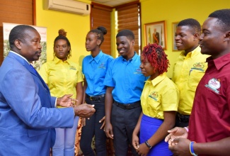 Transport and Mining Minister, Hon. Robert Montague (left), speaking with award recipients under the inaugural Jamaica Bauxite Institute (JBI)/Alcan Rio Tinto Legacy Fund Scholarship Programme at the signing ceremony at the Ministry's office in St. Andrew on Thursday (May 2). The students, who attend the Portland-based College of Agriculture, Science and Education (CASE), are (from left) Brittany Wisdom; Shevene Gibson; Allister Gardener; Shanile Scott; Rodane Nuwell and Lataneil Hamilton. 