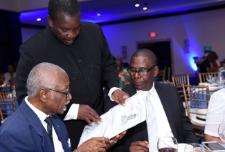 Transport and Mining Minister, Hon. Robert Montague (standing), in conversation with (from left) former Chief Executive Officer and Managing Director of Aeronautical Telecommunications Limited (AEROTEL), Wilfred Roberts, and Regional Operations Manager for AEROTEL’s Montego Bay office, David Miller, during the entity’s 40th anniversary long service and awards banquet at the Jamaica Pegasus Hotel in New Kingston, on Saturday (June 1). Mr. Miller, who received an award for serving the entity for 29 years, was among the 41 managers and staff recognized for between 10 and 30 years’ service.