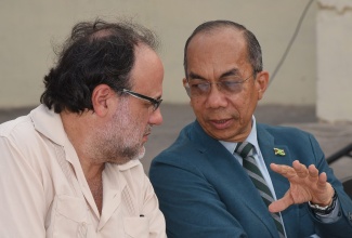 Minister of National Security, Hon. Dr. Horace Chang (right), in discussion with Member of Parliament for South St. Andrew, Mark Golding, shortly before the start of a  community meeting at the Ambassador Theatre in Trench Town on Wednesday (June 12). The meeting was convened to provide details about the Government’s proposed construction of the Police Plaza at No Man’s Land in downtown Kingston and to allow residents to pose questions to the Minister regarding the development. 