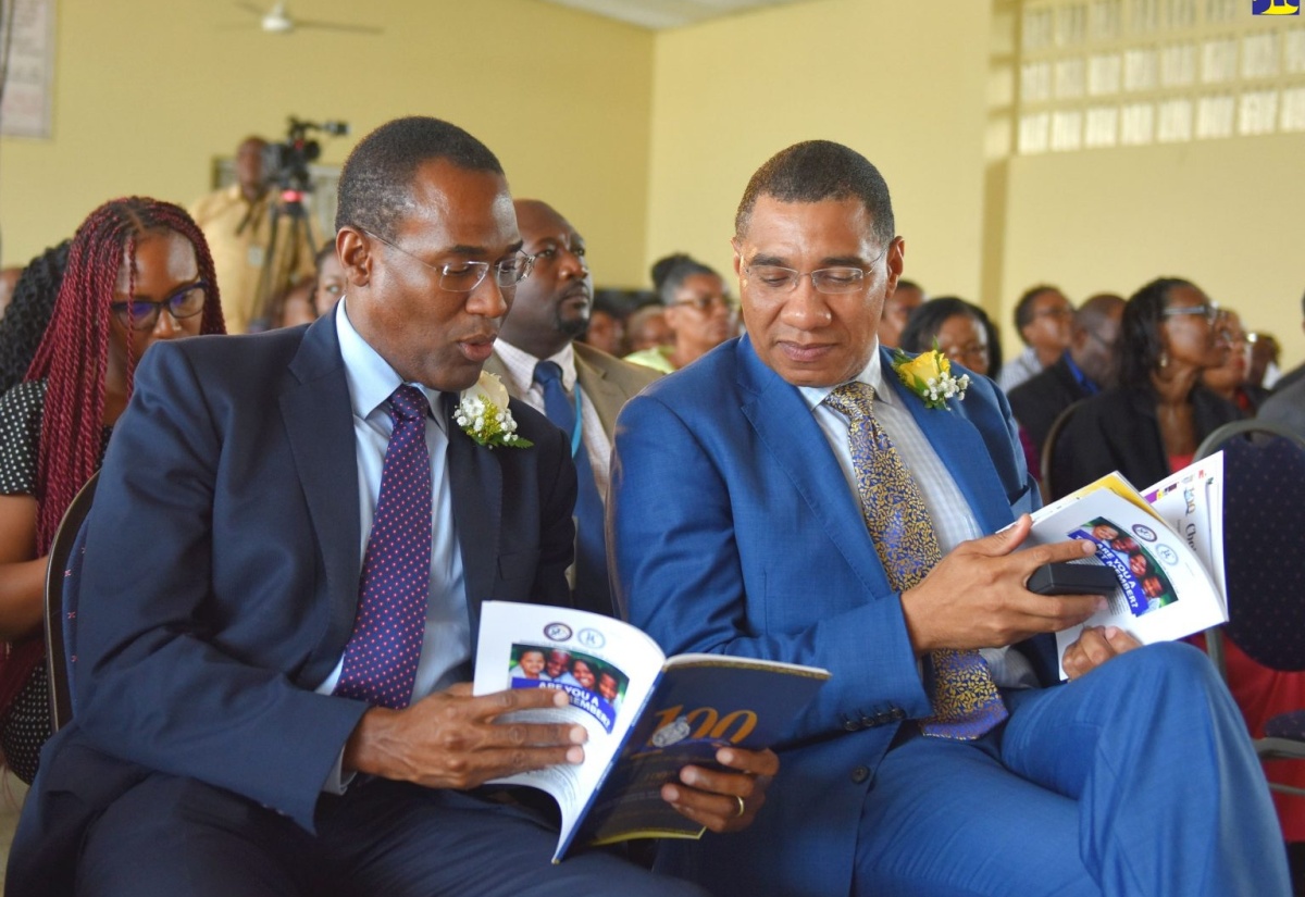 Prime Minister, the Most Hon. Andrew Holness (right), in discussion with the Minister of Finance and the Public Service,  Dr. the Hon. Nigel Clarke, as he peruses the 2018/19 annual report of the Jamaica Civil Service Association (JCSA). Occasion was the opening of the 100th annual general meeting of the association at the JACISERA Park Sport Complex in Kingston on Thursday (May 30).