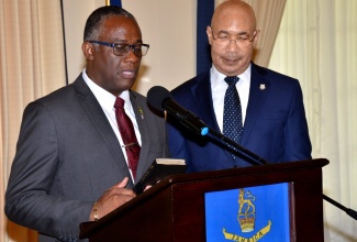 Governor-General, His Excellency, the Most Hon. Sir Patrick Allen (right), looks on as Manchester businessman and newly appointed Custos Rotulorum for the parish, Garfield Green, takes and subscribes to the Oath of Allegiance and Oath of Office, during Monday’s (June 24) swearing-in ceremony at King’s House.