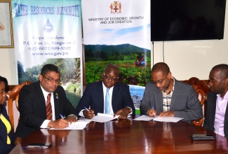 Minister without Portfolio in the Ministry of Economic Growth and Job Creation, Senator the Hon. Pearnel Charles Jr. (centre), affixes his signature to a memorandum of understanding (MOU), between the Water Resources Authority (WRA) and the Meteorological Service, today (July 17), at his New Kingston offices. This will allow for the provision of improved service in emergency preparation and response, through data sharing. Others (from left) are Chief Technical Director in the Ministry, Doreen Prendergast; Managing Director of the WRA, Peter Clarke; Head of the Meteorological Service of Jamaica, Evon Thompson, and another Chief Technical Director in the Ministry, Yanique Watson.