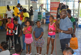 Minister without Portfolio in the Ministry of Economic Growth and Job Creation, Senator the Hon. Pearnel Charles Jr. (right),  engages with children at a community health fair held at the Glendevon Primary and Junior High School in St. James on Sunday, July 14.