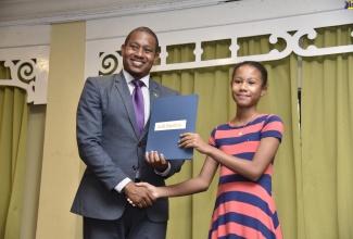 Minister of State in the Ministry of Industry, Commerce, Agriculture and Fisheries, Hon. Floyd Green (left), presents a bursary to  Jodi Dasilva.  
Occasion was the 2019 Jamaica Public Service (JPS) and Partners Co-Operative Credit Union's (PCCU) bursary and scholarship award ceremony on Thursday (August 8) at The Knutsford Court Hotel, New Kingston. 
