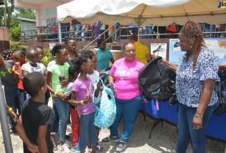 Chief Executive Officer (CEO) for the Child Protection and Family Services Agency (CPFSA), Rosalee Gage-Grey (2nd right), and the entity’s Director of Alternate Care Services, Eunice Scott-Shaw (right), hand out school supplies to children during the CPFSA’s Western Region Back to School Treat and Health Fair, which was held at Holly Hill Infant and Primary School in Darliston, Westmoreland, on Friday (August 23).