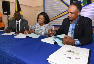 Assistant Commissioner of Police (ACP), Warren Clarke (left); Member of Parliament for North Central St. Catherine, Natalie Neita (centre), and Managing Director of the Jamaica Social Investment Fund (JSIF), Omar Sweeney, participate in the contract signing for the $88 million upgrading of the Bog Walk Police Station and Bog Walk Health Centre, and rehabilitation of the Pineapple Lane road, yesterday (August 15), at the Knollis Community Centre, in St. Catherine. 