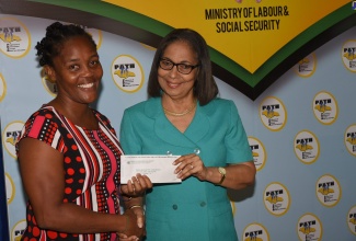 Minister of Labour and Social Security, Hon. Shahine Robinson (right), presents mother of five, Sara Lemonious, with a cheque. Occasion was the handover of cheques under the Ministry’s Back-to-School grant for the Programme of Advancement Through Health and Education (PATH) beneficiaries on Friday (August 16) at the Ministry, in Kingston. The Ministry will be disbursing $569.289 million to 162,654 children registered under  PATH.