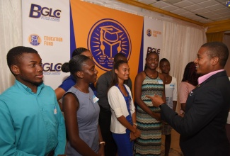 Minister of State in the Ministry of Industry, Commerce, Agriculture and Fisheries (right), interacts with the top-10 performing Betting, Gaming and Lotteries Commission (BGLC) scholarship recipients, at the Commission’s Education Fund ‘Meet and Greet’, held  at the Mona Visitors’ Lodge on August 28.   