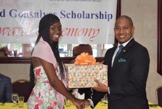 Minister of State in the Ministry of Industry, Commerce, Agriculture and Fisheries, Hon. Floyd Green, receives a gift basket from former scholarship recipient, Shannaia McDowell, following his keynote address at the Gateway Co-operative Credit Union sponsored Enid Gonzales Primary Exit Profile (PEP) Scholarship luncheon and awards Ceremony, in Montego Bay, on August 15.