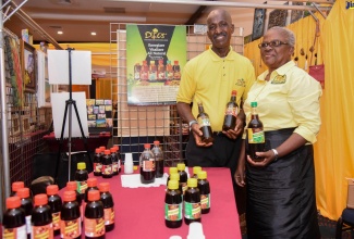 Chief Executive Officer, Wood Land Roots Natural Drinks, Oliver Welsh (left), and one of his assistants, Kathleen Brown, display some of his products at the recent Jamaica Business Development Corporation (JBDC) Expo 2019, held at The Jamaica Pegasus hotel in New Kingston.    
